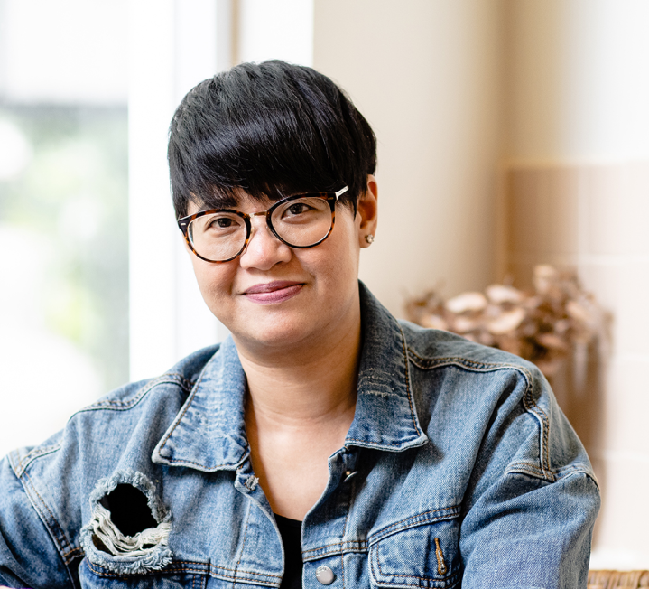 A woman wearing glasses and a denim jacket.