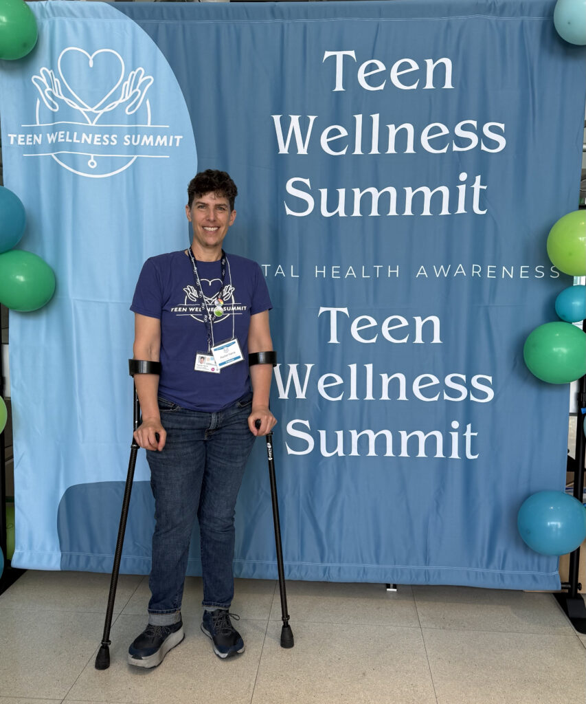 Academic coordinator at UCSF stands in front of a blue backdrop that reads Teen Wellness Summit.