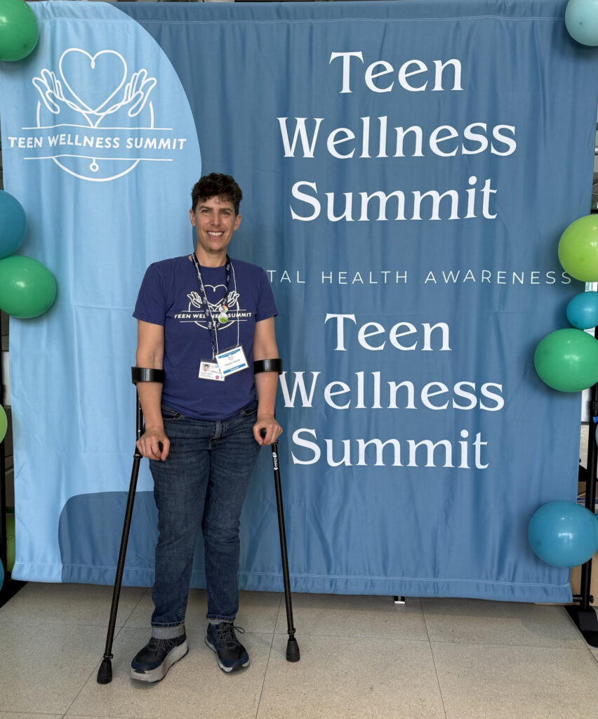 Academic coordinator at UCSF stands in front of a blue backdrop that reads Teen Wellness Summit.