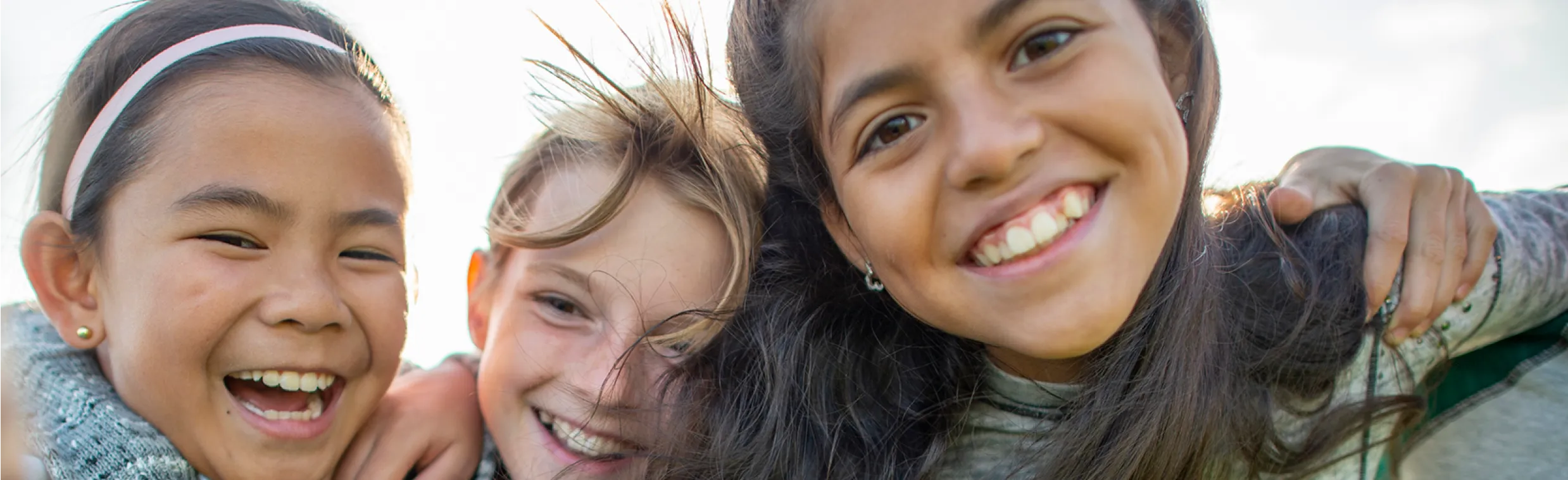 A group of young girls with arms around eachother smiling.